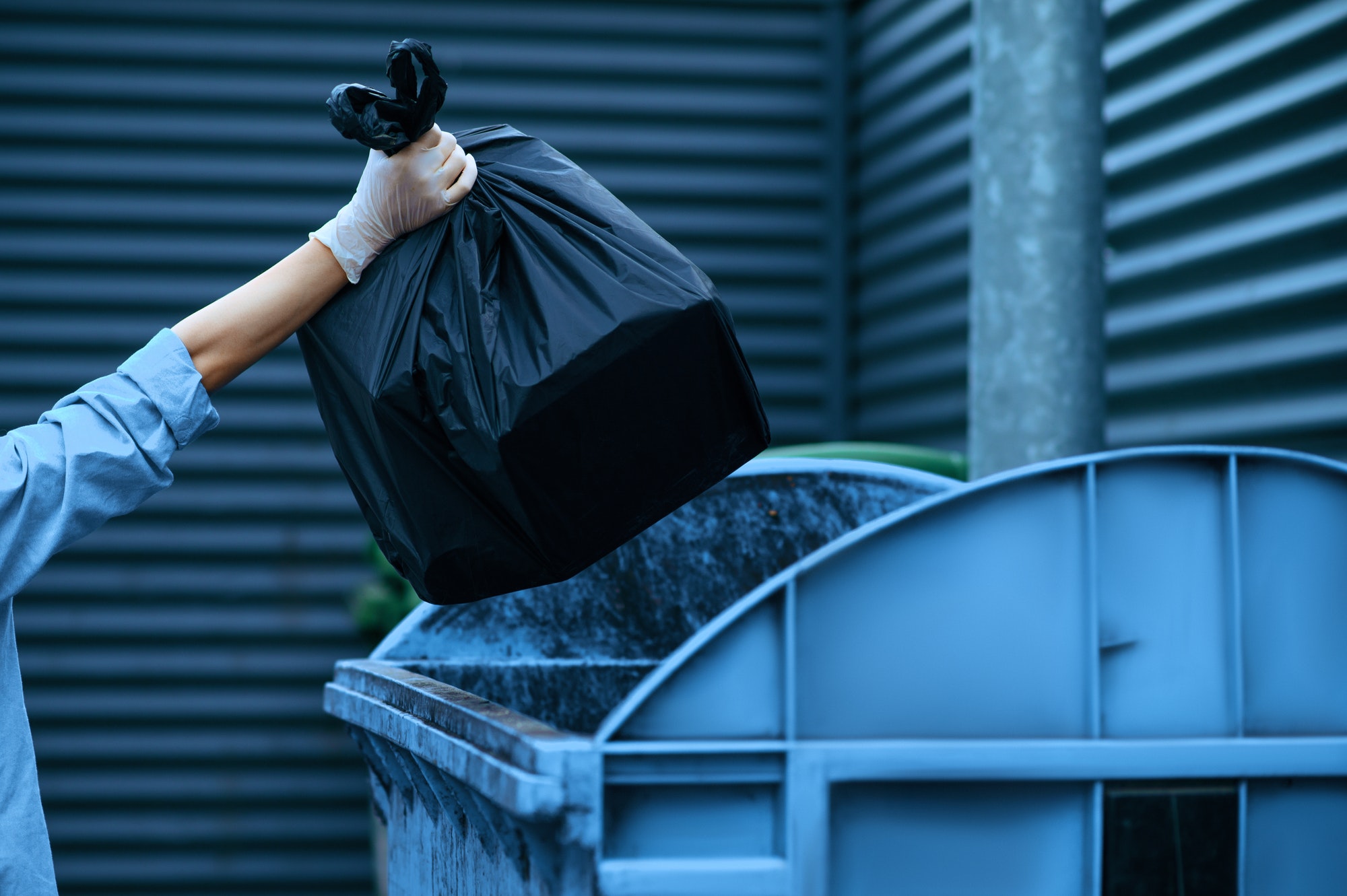 Volunteer puts plastic trash bag into the bin